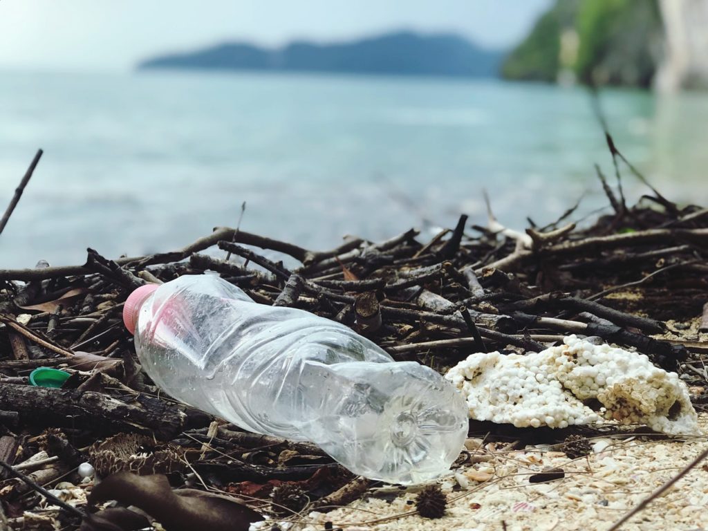 A trashed plastic bottle on a beach. This picture illustrate the importance of living plastic-free lives.