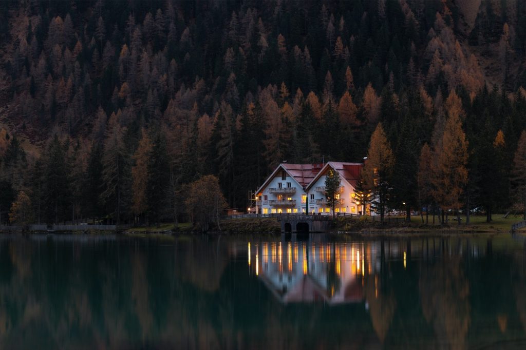 A picture of a big beautiful house with by a lake.